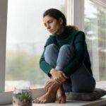 Kiedy sąd może ograniczyć prawa rodzicielskie matce? Przesłanki i procedura Zamyślona kobieta siedząca przy oknie – ograniczenie praw rodzicielskich matki